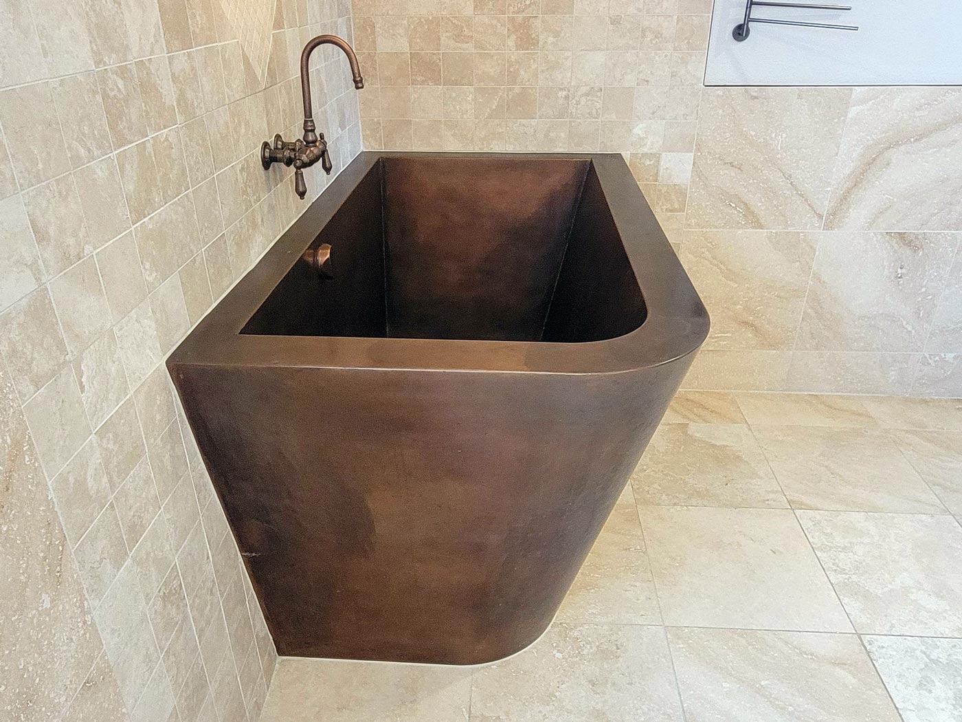 Custom copper Japanese bath with two-sided tapered skirting and bench seating.  42”x 60”x 36”